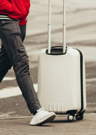 Guy holding a white luggage towards Italy